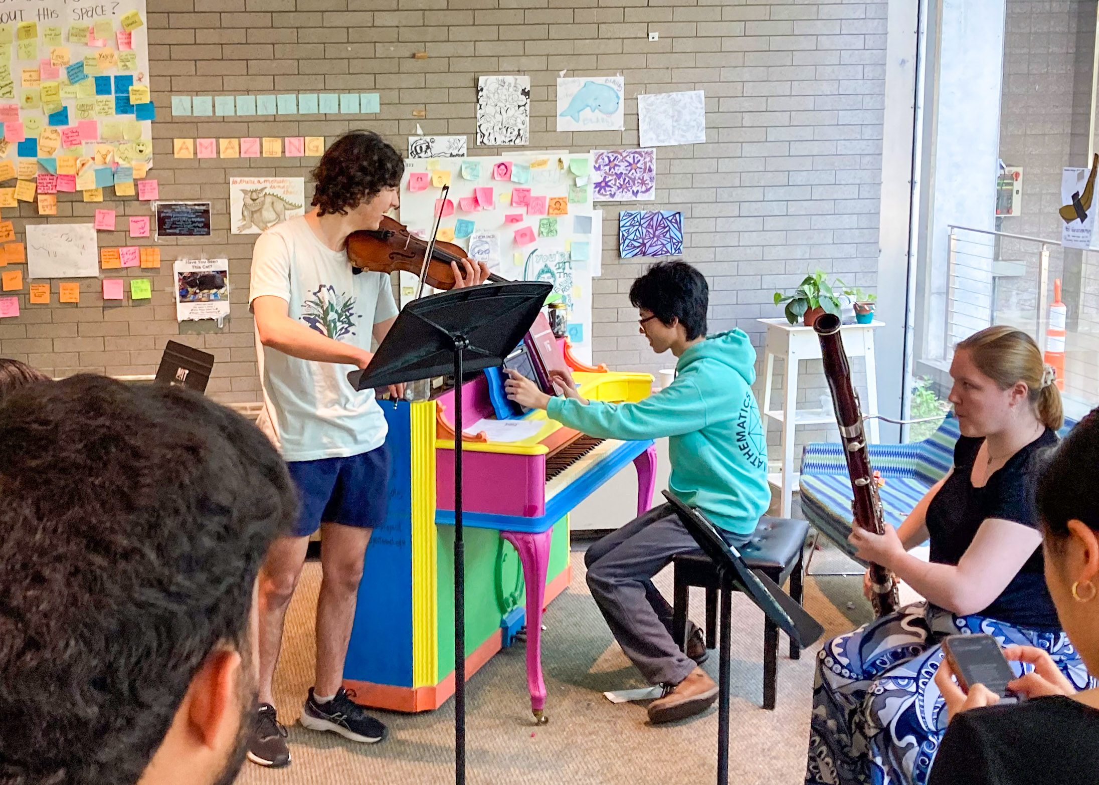 performers playing a violin, a piano and an oboe while students watch