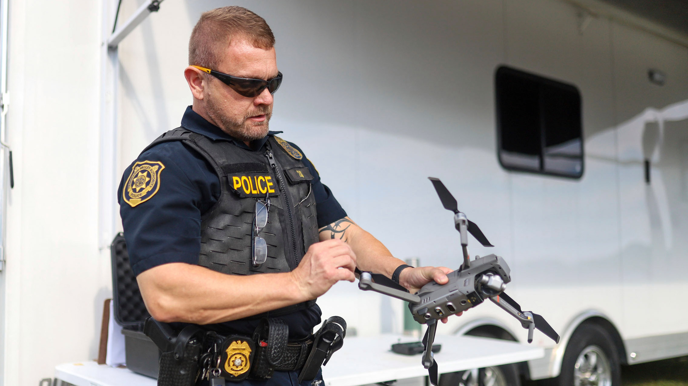 a police officer in sunglasses holds a quadcopter drone