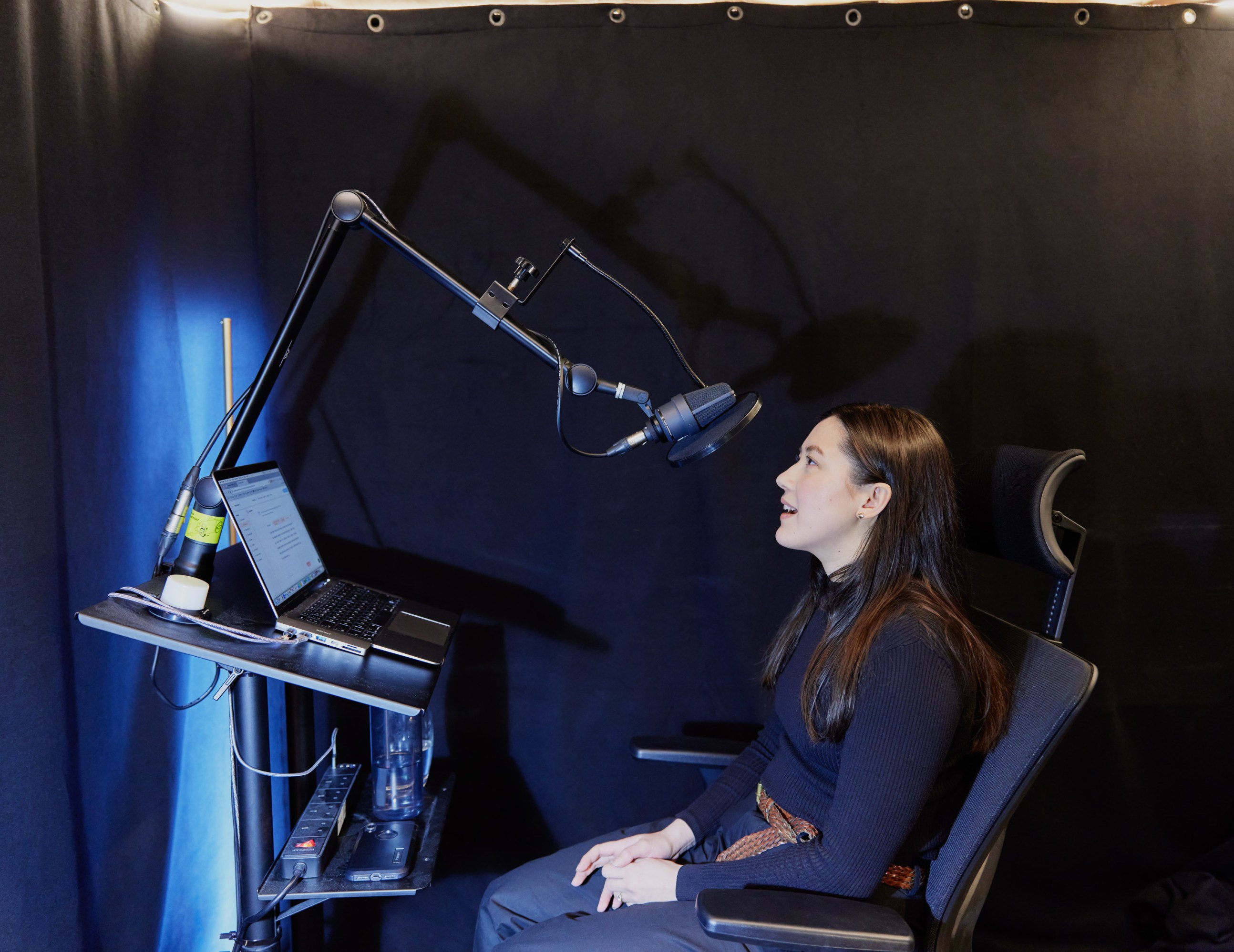 Melissa recording audio into a boom mic seated in front of a laptop stand