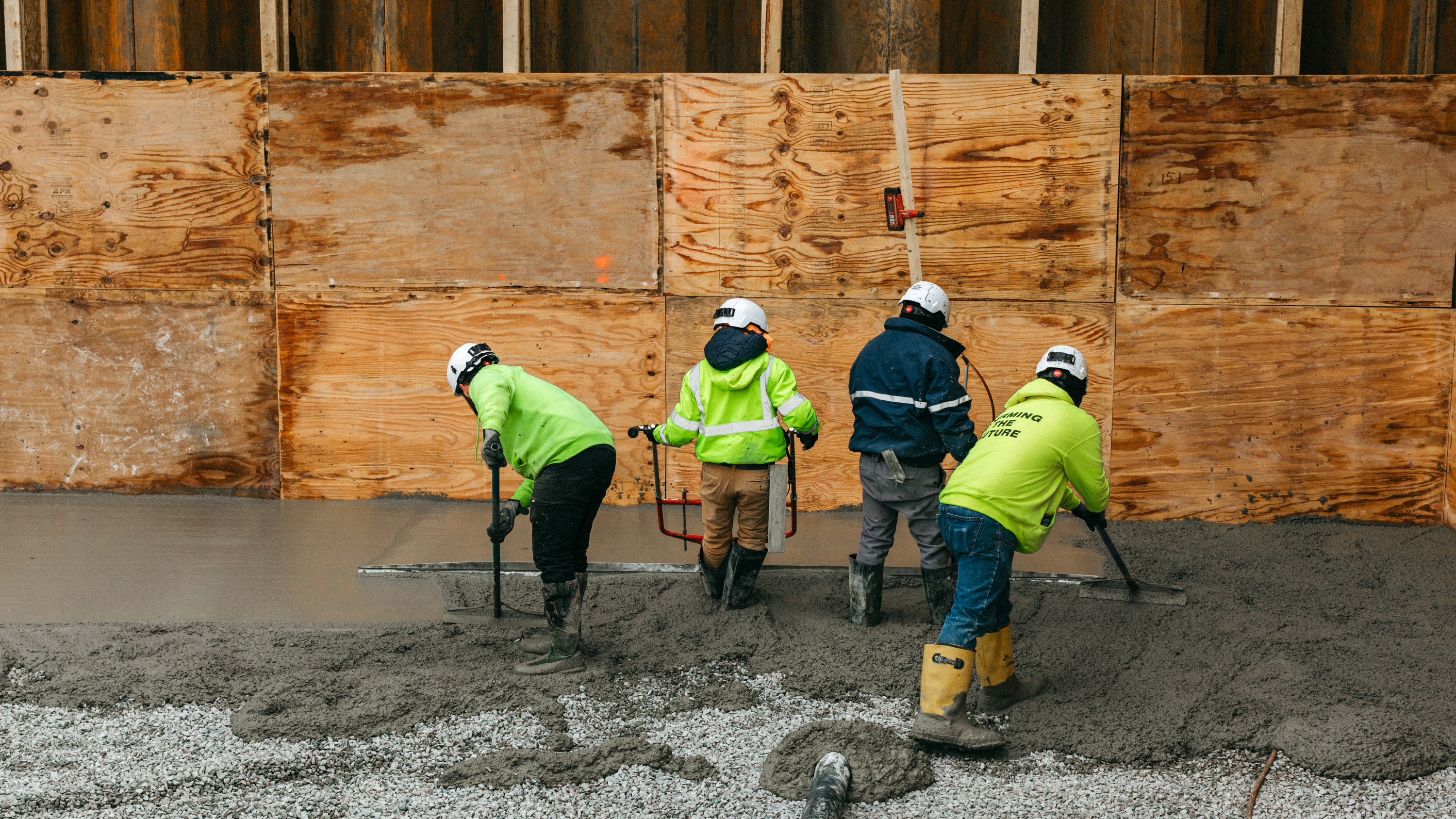 four workers spreading concrete