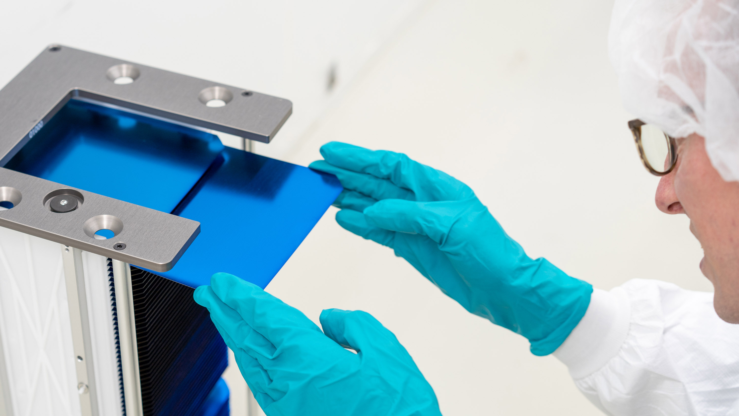 closeup on a worker in a clean suit loading a tandem cell into a holder