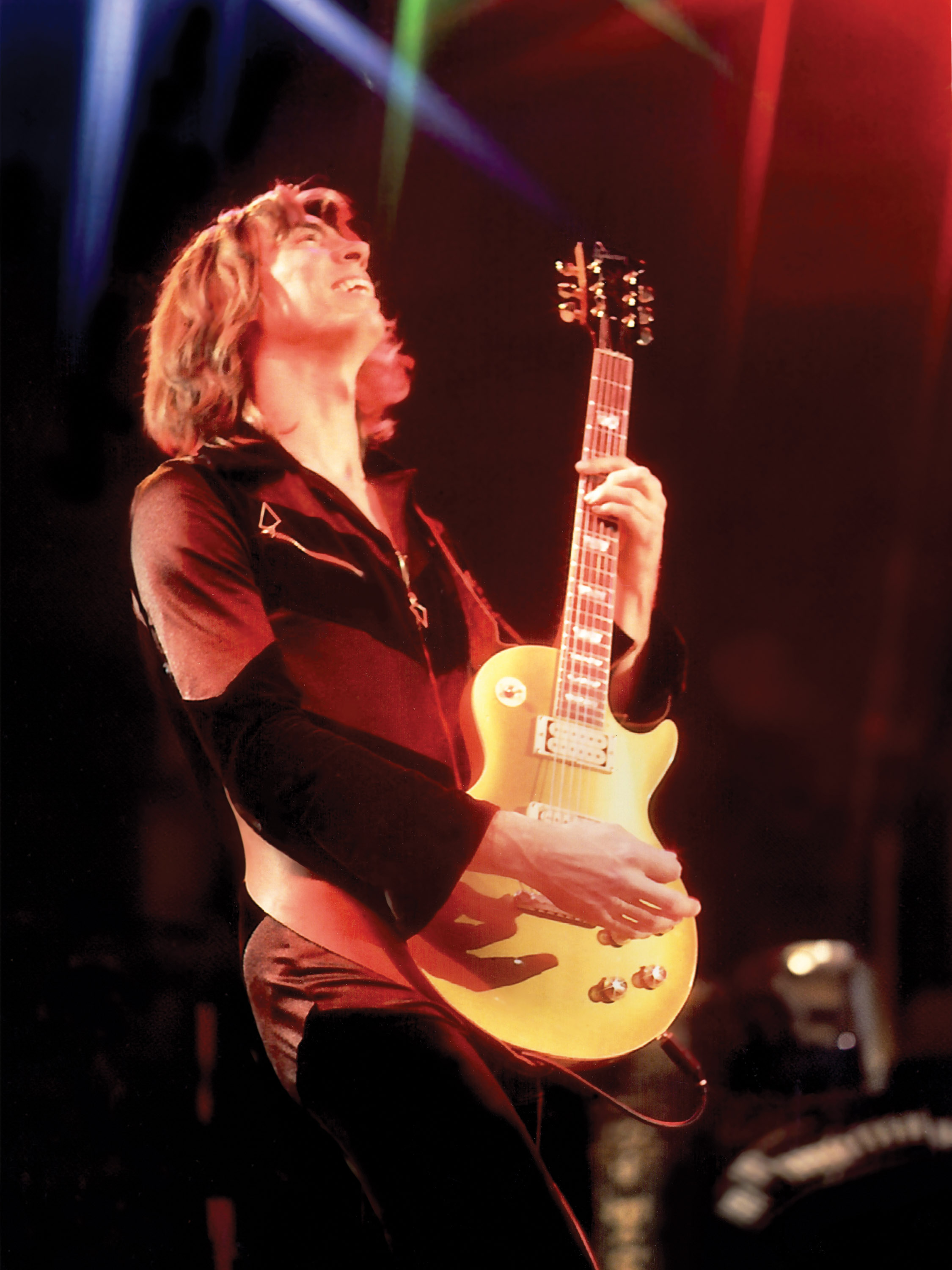 Tom Scholz performing on stage with guitar